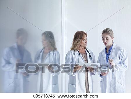 Stock Photography - Two female doctors discussing medical notes. Fotosearch