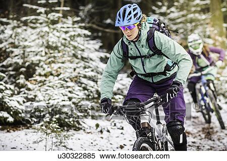 Two female mountain bikers riding through forest in snow View Large Photo Image Stock Photography - Two female mountain bikers riding through forest in snow. Fotosearch