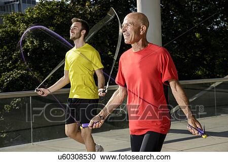 Stock Image - Two male athletes exercising with skipping ropes. Fotosearch
