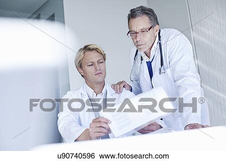 Two male doctors looking at medical notes View Large Photo Image Stock Photograph - Two male doctors looking at medical notes. Fotosearch