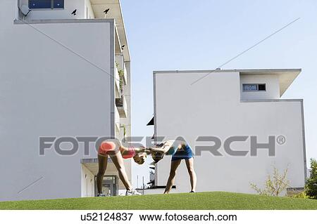 Two young female athletes exercising in park View Large Photo Image Stock Photo - Two young female athletes exercising in park. Fotosearch