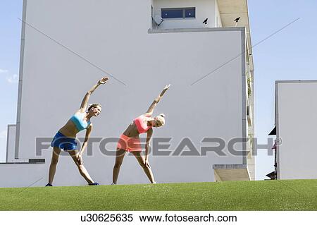 Two young female athletes stretching in park View Large Photo Image Stock Photography - Two young female athletes stretching in park. Fotosearch