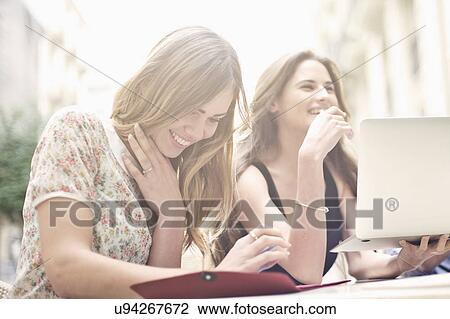 Two young female friends enjoying a break at sidewalk cafe, Valencia, Spain View Large Photo Image Stock Image - Two young female friends enjoying a break at sidewalk cafe, Valencia, Spain. Fotosearch