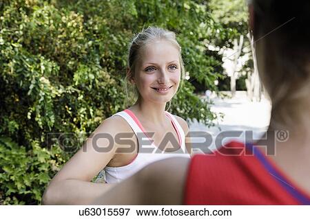 Stock Photo - Two young female runners taking a break in park. Fotosearch