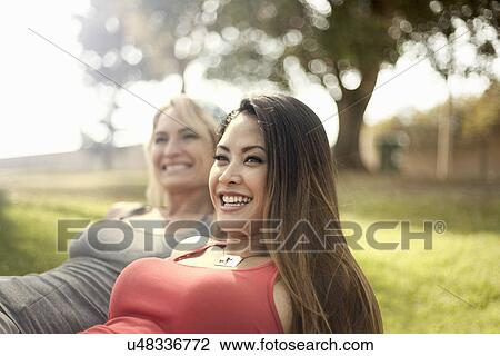 Two young women enjoying sunshine in park View Large Photo Image Stock Image - Two young women enjoying sunshine in park. Fotosearch