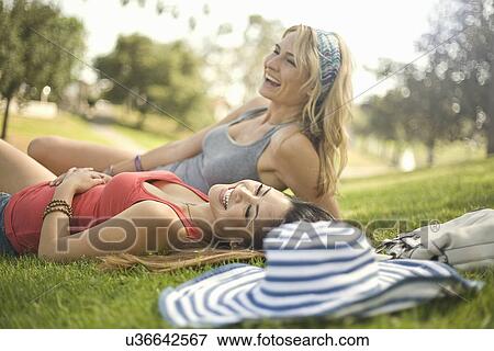 Two young women having fun and relaxing on park grass View Large Photo Image Stock Photo - Two young women having fun and relaxing on park grass. Fotosearch
