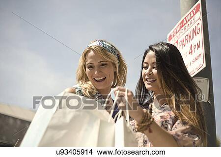 Two young women on street looking in shopping bags View Large Photo Image Picture - Two young women on street looking in shopping bags. Fotosearch