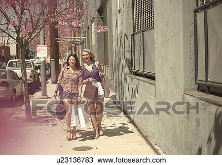 Stock Image - Two young women out shopping in the city. Fotosearch