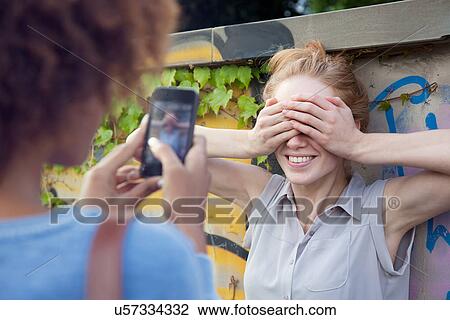 Stock Image - Two young women photographing with smartphone. Fotosearch