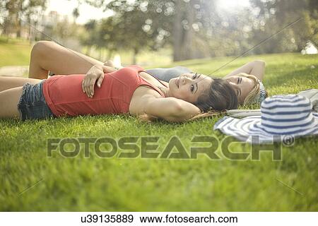 Stock Photo - Two young women relaxing on park grass. Fotosearch