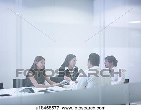 Stock Photo - View through glass wall of business colleagues in meeting. Fotosearch