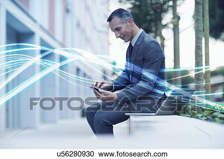 Stock Image - Waves of blue light and businessman texting on smartphone. Fotosearch