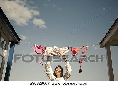 Woman hanging swimwear on washing line, Southwold, Suffolk, UK View Large Photo Image Stock Photo - Woman hanging swimwear on washing line, Southwold, Suffolk, UK. Fotosearch
