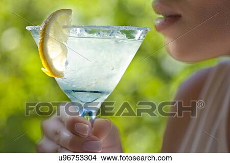 Picture - Woman holding glass of margarita to mouth. Fotosearch