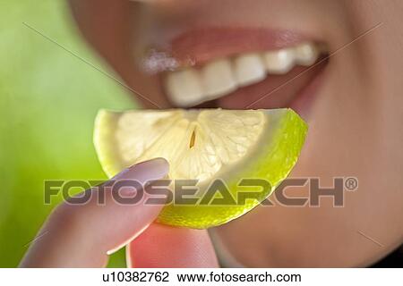 Woman holding slice of lime to mouth View Large Photo Image Stock Image - Woman holding slice of lime to mouth. Fotosearch
