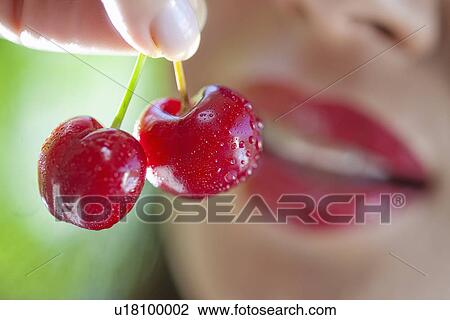 Stock Image - Woman holding up cherries. Fotosearch