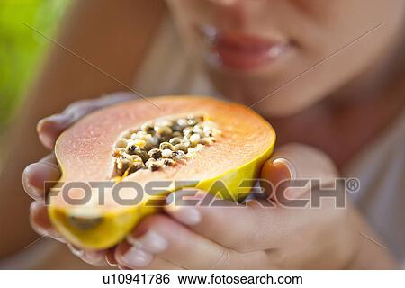 Stock Photograph - Woman holding up halved papaya. Fotosearch