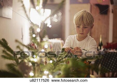 Stock Photograph - Young boy decorating christmas tree. Fotosearch