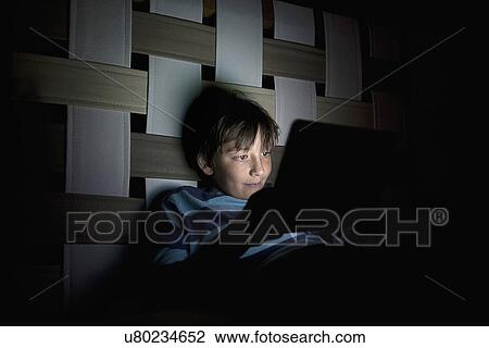 Young boy in bedroom at night using digital tablet View Large Photo Image Stock Image - Young boy in bedroom at night using digital tablet. Fotosearch