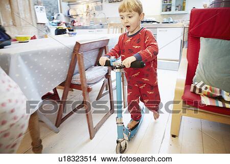 Young boy playing on scooter in kitchen View Large Photo Image Picture - Young boy playing on scooter in kitchen. Fotosearch