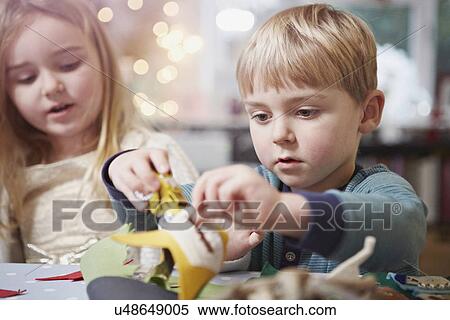 Stock Photography - Young brother and sister crafting at kitchen table. Fotosearch