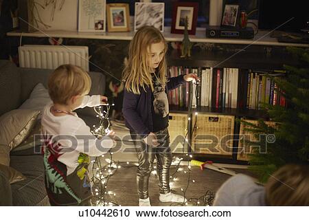 Stock Image - Young brother and sister untangling christmas lights. Fotosearch