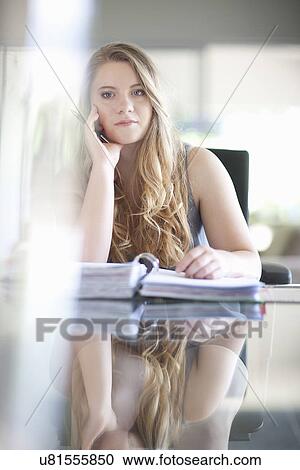 Stock Image - Young businesswoman looking bored with paperwork. Fotosearch