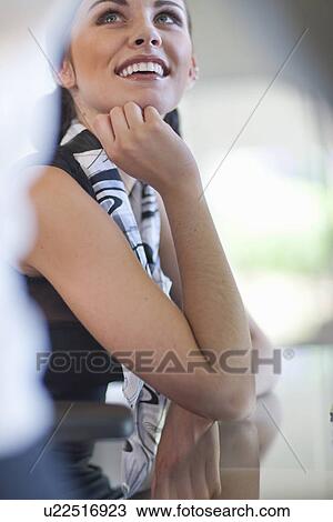 Stock Image - Young businesswoman looking up from desk. Fotosearch