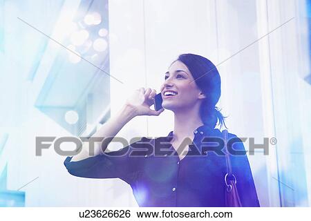 Young businesswoman talking on smartphone with lights coming out of it View Large Photo Image Stock Photograph - Young businesswoman talking on smartphone with lights coming out of it. Fotosearch