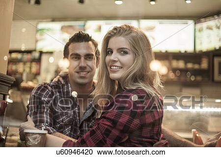Stock Image - Young couple looking out of cafe window. Fotosearch