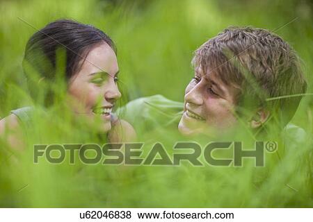 Stock Photo - Young couple lying in long grass. Fotosearch