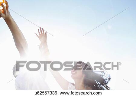 Stock Photograph - Young couple playing in sunlight, low angle view. Fotosearch