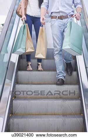 Stock Image - Young couple shopping in mall. Fotosearch