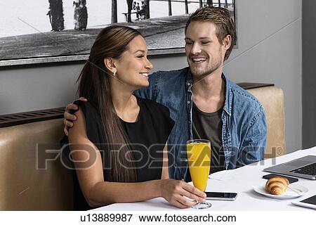 Young couple sitting in cafe with technology on table View Large Photo Image Stock Photo - Young couple sitting in cafe with technology on table. Fotosearch