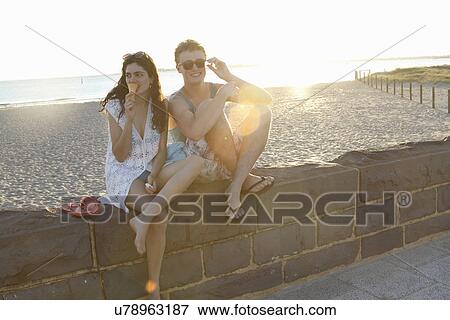 Young couple sitting on wall, Port Melbourne, Melbourne, Australia View Large Photo Image Stock Photo - Young couple sitting on wall, Port Melbourne, Melbourne, Australia. Fotosearch