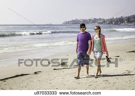 Young couple strolling on beach, Laguna Beach, California, USA View Large Photo Image Stock Image - Young couple strolling on beach, Laguna Beach, California, USA. Fotosearch