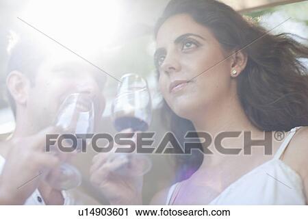 Stock Image - Young couple wine tasting at vineyard. Fotosearch