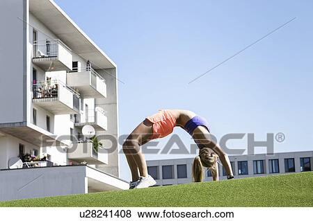 Stock Photo - Young female athlete bending over backwards in park. Fotosearch