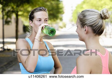 Young female athletes taking a break on street View Large Photo Image Stock Image - Young female athletes taking a break on street. Fotosearch