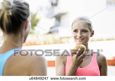 Stock Photo - Young female athletes taking a break and chatting. Fotosearch