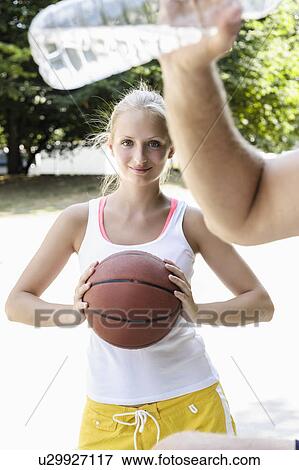 Stock Photo - Young female basketball player taking a break in park. Fotosearch