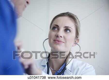 Young female doctor holding stethoscope to patients chest View Large Photo Image Stock Photo - Young female doctor holding stethoscope to patients chest. Fotosearch