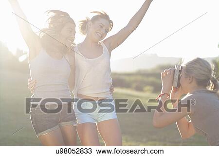 Young female friends posing for photographs View Large Photo Image Stock Image - Young female friends posing for photographs. Fotosearch