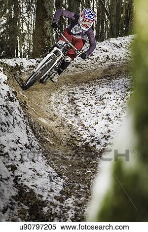 Stock Photography - Young female mountain biker riding a forest dirt track. Fotosearch