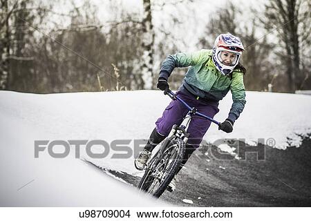 Picture - Young female mountain biker riding in snow. Fotosearch