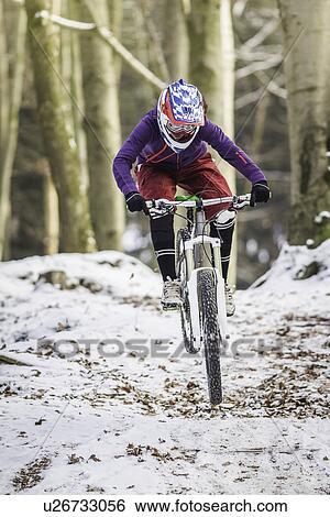 Stock Photograph - Young female mountain biking in winter forest. Fotosearch