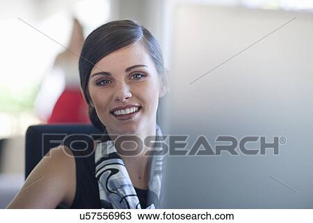 Stock Image - Young female office worker at computer. Fotosearch