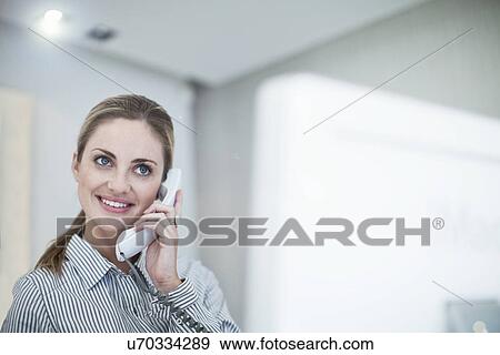Young female office worker using land line telephone View Large Photo Image Stock Photo - Young female office worker using land line telephone. Fotosearch