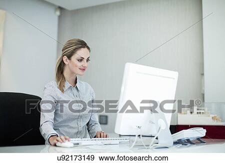 Young female receptionist working on computer View Large Photo Image Stock Photo - Young female receptionist working on computer. Fotosearch