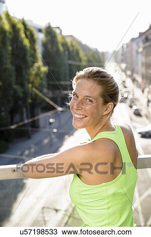 Stock Image - Young female runner taking a break on city footbridge. Fotosearch